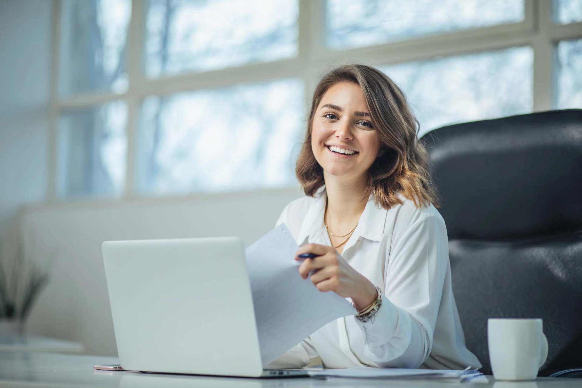 A women in a lawyers office smiling while holding paper