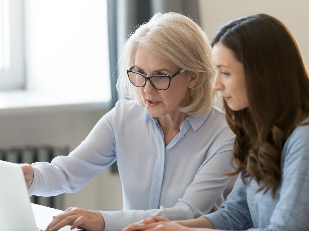 older woman sitting with a younger female both looking at computer